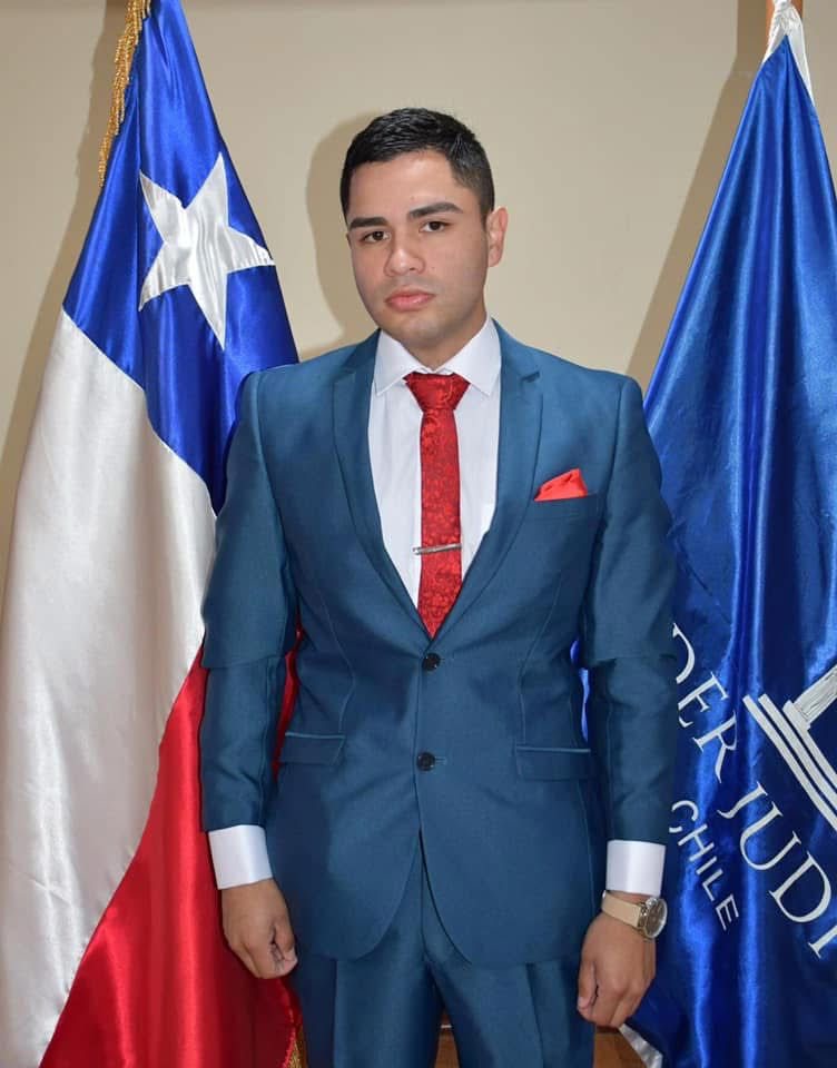 Retrato profesional de William David Díaz Gálvez con traje, junto a banderas.